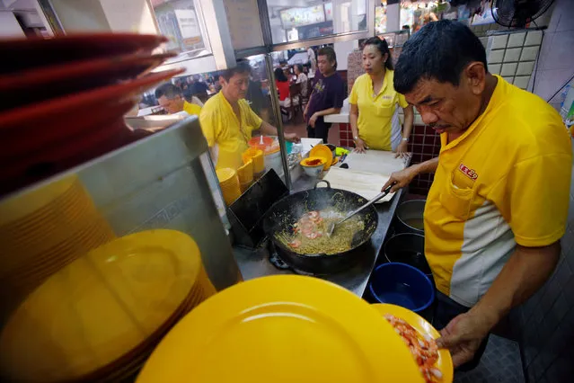 Hawker Alex See, 66, and his daughter Penny See, 33, cooking at their Geylang Lorong 29 Fried Hokkien Mee stall at East Coast Road in Singapore August 10, 2016. “Young people come and go, they are not serious about learning. When I was helping my father at the age of 16, I asked him so many questions everyday to learn so that I can one day beat him at it. I do not think I have beaten my old man yet, it's a tie”, See said. (Photo by Edgar Su/Reuters)