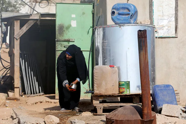 A Palestinian woman washes a pot from a tank outside her house on the outskirts of the West Bank village of Yatta, south of Hebron, August 17, 2016. (Photo by Mussa Qawasma/Reuters)