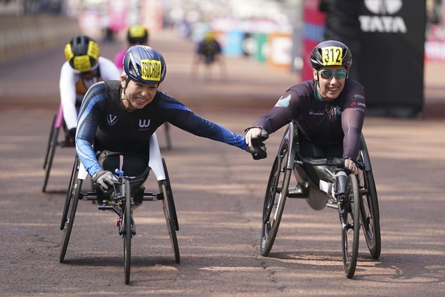 Wakako Tsuchida of Japan, left, who placed 9th and Patricia Eachus of Switzerland who placed 8th tap hands after finishing at the London Marathon, Sunday, April 27, 2025. (Photo by Alberto Pezzali/AP Photo)