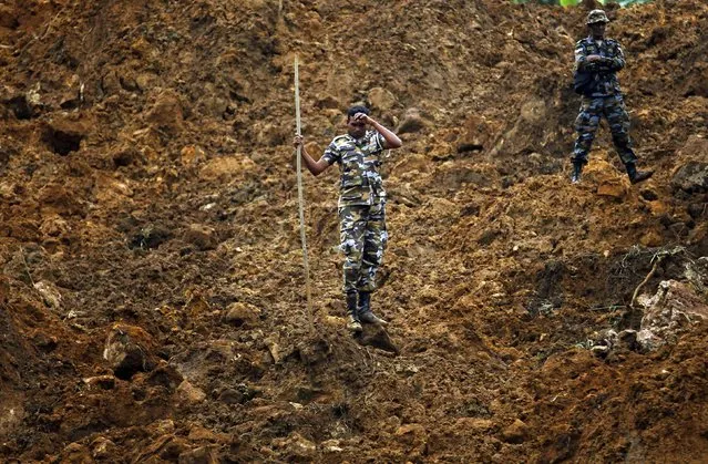A member of a military rescue team pauses during search operations at the site of a landslide at the Koslanda tea plantation near Haldummulla October 30, 2014. (Photo by Dinuka Liyanawatte/Reuters)