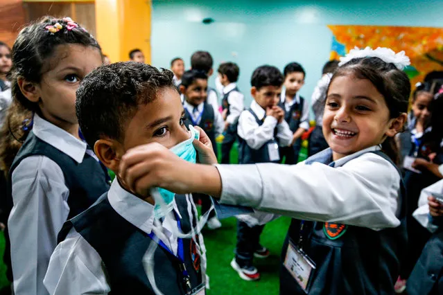 A girl applies a mask onto the face of another boy during an awareness session about COVID-19 coronavirus disease held by a local kindergarten in Gaza City on August 10, 2020, as education facilities in the Palestinian enclave re-opened for the new 2020-2021 academic year following an easing of pandemic restrictions. (Photo by Mohammed Abed/AFP Photo)