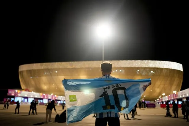 A man holds an Argentinian flag prior to the World Cup quarterfinal soccer match between the Netherlands and Argentina, outside the Lusail Stadium in Lusail, Qatar, Friday, December 9, 2022. (Photo by Natacha Pisarenko/AP Photo)
