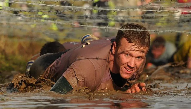 A competitor crawls under barbed wire during the Tough Guy Challenge endurance race on January 27, 2013 in Telford, England. Every year thousands of people run the 8 mile assault course which involves freezing temperatures, fire and ice.  (Photo by Michael Regan)
