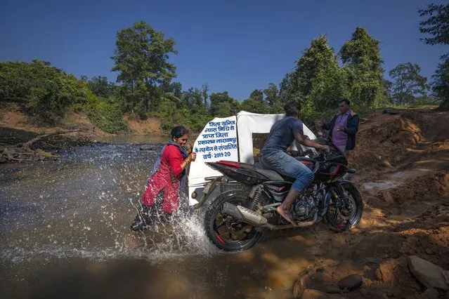 Lata Netam, a health worker, unsuccessfully tries to push a motorbike ambulance, up a steep riverbank through Abhujmarh, or “the unknown hills”, to reach a pregnant woman in Kodoli, a remote village near Orchha in central India's Chhattisgarh state, November 15, 2022. These ambulances, first deployed in 2014, reach inaccessible villages to bring pregnant women to an early referral center, a building close to the hospital where expectant mothers can stay under observation, routinely visit doctors if needed until they give birth. Since then the number of babies born in hospitals has doubled to a yearly average of about 162 births each year, from just 76 in 2014. The state has one of the highest rates of pregnancy-related deaths for mothers in India, about 1.5 times the national average, with 137 pregnancy related deaths for mothers per 100,000 births. (Photo by Altaf Qadri/AP Photo)