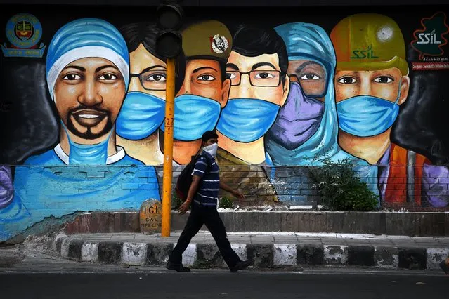 A man walks past a mural of frontline workers after the government eased a nationwide lockdown imposed as a preventive measure against the COVID-19 coronavirus in New Delhi on July 14, 2020. (Photo by Sajjad Hussain/AFP Photo)
