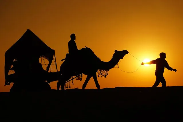 Silhouettes of Indian tourists are seen as they enjoying camel safari during the year's last sunset in Desert of Pushkar, Rajasthan, India on December 31, 2022. (Photo by Himanshu Sharma/Anadolu Agency via Getty Images)