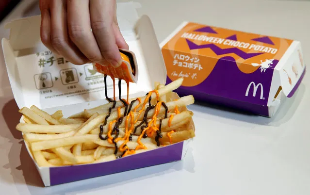 An employee of McDonald's Japan puts pumpkin and choco sauce on a McFry Potato to demonstrate their company's “Halloween Choco Fries – Pumpkin & Choco Sauce” in Tokyo, Japan, September 29, 2016. (Photo by Toru Hanai/Reuters)