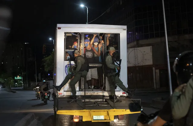 Men who were detained for not complying with COVID-19 regulations by breaking curfew or attending block parties, are transported in a police van to a coliseum, in the Petare neighborhood of Caracas, Venezuela, early Saturday, August 8, 2020, as part of an operation to educate residents on the risks of being out and socializing in groups amid the new coronavirus pandemic. Residents are released a few hours later after receiving instruction on best social distancing practices. (Photo by Ariana Cubillos/AP Photo)