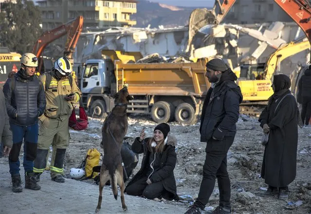 A woman plays with a sniffer dog as rRescue workers continue the search for victims of the earthquake in Antakya, Turkey, Saturday, February 11, 2023. Rescue crews on Saturday pulled more survivors, including entire families, from toppled buildings despite diminishing hopes as the death toll of the enormous quake that struck a border region of Turkey and Syria five days continued to rise. (Photo by Lefteris Pitarakis/AP Photo)