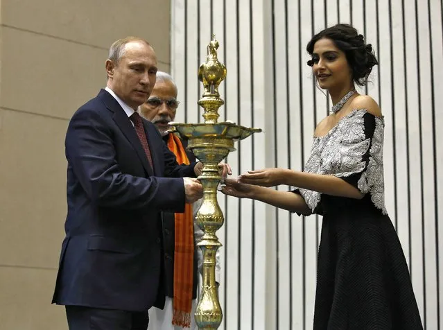 Bollywood actress Sonam Kapoor (R) helps Russian President Vladimir Putin (L) to light a traditional Indian oil lamp as India's Prime Minister Narendra Modi watches during the inauguration of World Diamond Conference in New Delhi December 11, 2014. Modi told Putin on Thursday that Russia will remain India's top defence supplier, even though New Delhi's options had improved since the end of the Cold War. (Photo by Ahmad Masood/Reuters)