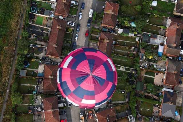 A hot air balloon flies over a residential area during a mass launch at the annual Bristol International Balloon Fiesta, in Bristol, Britain, on August 8, 2025. (Photo by Toby Melville/Reuters)