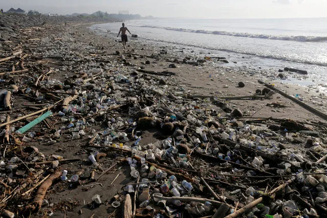 A local resident walks along a section of Matahari Terbit beach covered in plastic and other debris washed ashore by seasonal winds near Sanur, Bali, Indonesia April 11, 2018. (Photo by Johannes P. Christo/Reuters)