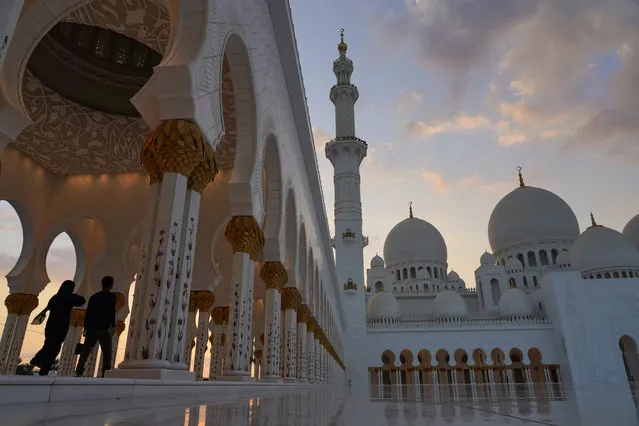 Tourists walk through Sheikh Zayed Grand Mosque at dusk in Abu Dhabi, United Arab Emirates, Wednesday, December 9, 2020. Abu Dhabi announced Wednesday it would resume “all economic, tourism, cultural and entertainment activities in the emirate within two weeks”. It attributed the decision to “successes” in halting the spread of the coronavirus. (Photo by Jon Gambrell/AP Photo)