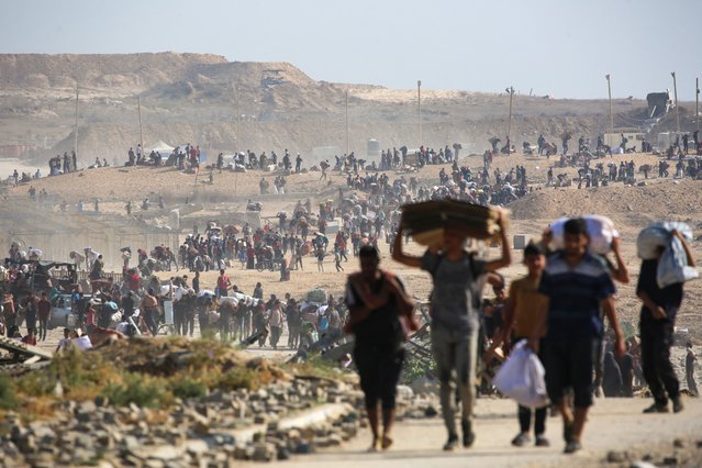 People walk with bags of humanitarian aid they received at a distribution centre run by the US and Israeli-backed Gaza Humanitarian Foundation (GHF), at the so-called “Netzarim corridor”, in Nuseirat in the central Gaza Strip, on September 26, 2025. The Israeli military said on September 25 that 700,000 Palestinians have fled Gaza City since late August, as it presses an air and ground assault on the urban centre. (Photo by Eyad Baba/AFP Photo)