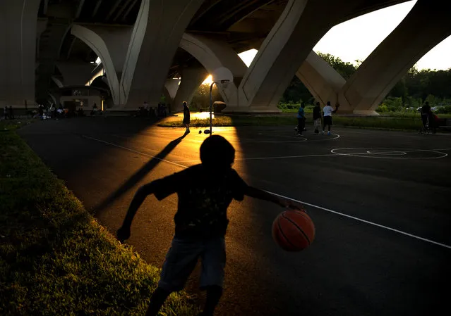 Evening light cast long shadows of players on a basketball court  at Jones Point Park beneath Woodrow Wilson Bridge in Alexandria, Virginia, on Saturday, June 26, 2014. (Photo by Nikki Kahn/The Washington Post)
