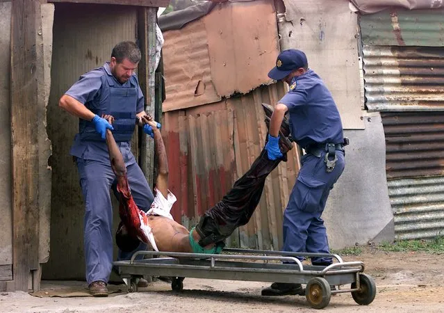 South African police carry the body of a man who was shot dead by unknown gunmen at the Mandela Squatter Camp in Kathlehong east of Johannesburg during the local government elections, December 5, 2000. (Photo by Juda Ngwenya/Reuters)
