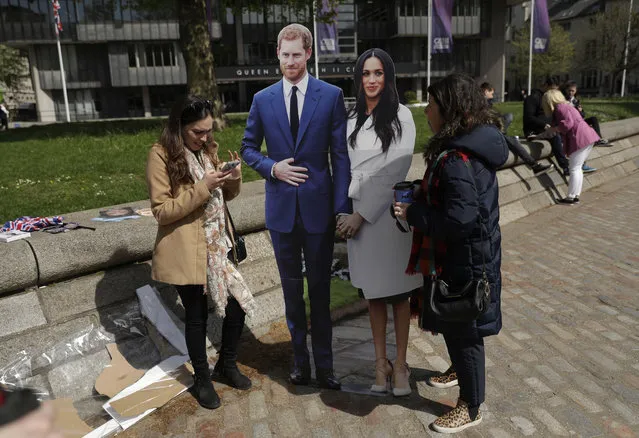 Tourists stand to have their photo taken with cardboard cutouts of Britain's Prince Harry and his fiancee Meghan Markle, that a television company were using to film a programme in London, Thursday, May 3, 2018. The couple are due to get married in Windsor on Saturday May 19. (Photo by Matt Dunham/AP Photo)