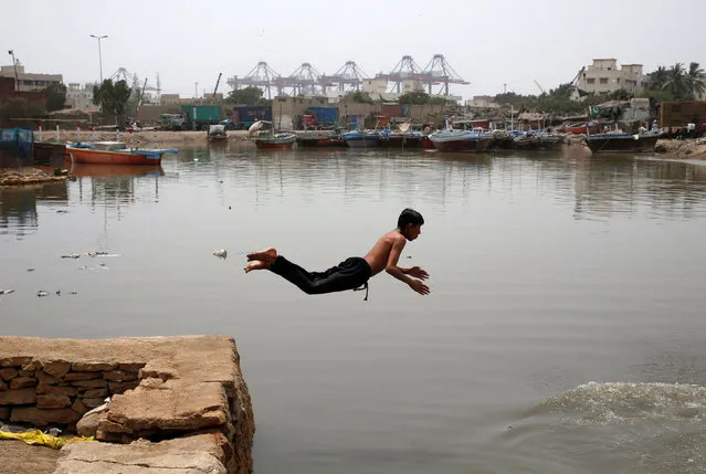 A boy jumps into the water to cool off during hot and humid weather, at a port area in Karachi, Pakistan May 3, 2018. (Photo by Akhtar Soomro/Reuters)