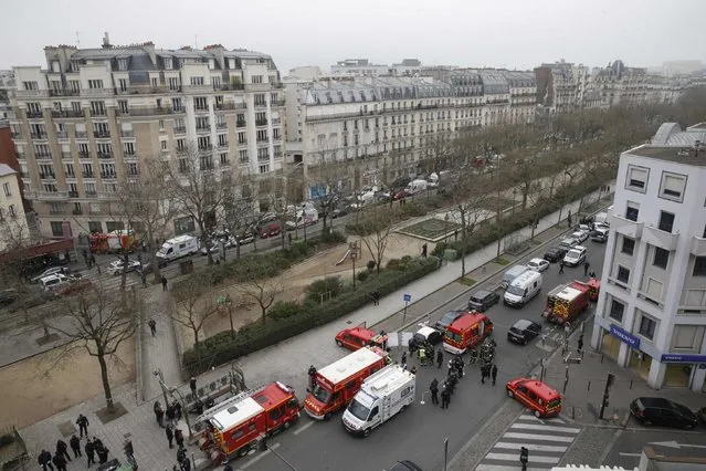 Police and rescue forces are seen near the scene after a shooting at the Paris offices of Charlie Hebdo, a satirical newspaper, January 7, 2015. (Photo by Christian Hartmann/Reuters)