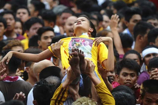 Devotees of the Black Nazarene lifts-up a woman who fainted during an annual procession in Manila January 9, 2015. (Photo by Ezra Acayan/Reuters)