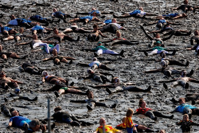 Participants take part for a world record in making mud angels as part of the 2024 Mud Flats Olympics (20. Wattoluempiade) on August 17, 2024 near Brunsbuetel, Germany. This the twentieth year the Mud Flats Olympics are taking place. Organizers, who say they are getting old, claim it is the last. The event raises money for local charities. (Photo by Morris MacMatzen/Getty Images)