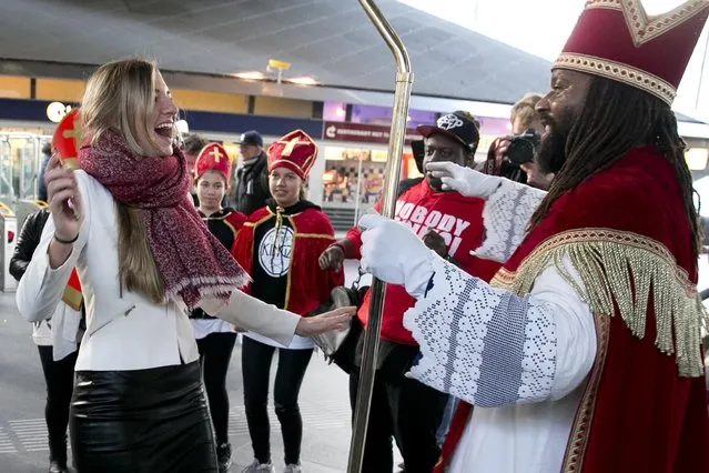 Sinterklaas, traditionally played by a white person, dances with a woman at subway station in Amsterdam, Netherlands, Saturday, November 5, 2016. (Photo by Peter Dejong/AP Photo)