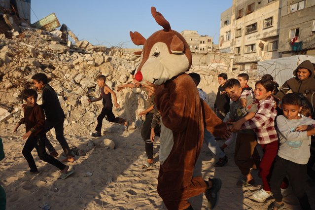 Palestinian refugees take part during a film screening and children's entertainment event held as part of the Gaza Children's Film Festival, organized by the Masharawi Film Fund for Films and Filmmakers, on the ruins of the Beach Services Sports Club in Al-Shatee refugee camp, west of Gaza City on November 23, 2025. (Photo by Omar Al-Qattaa/AFP Photo)