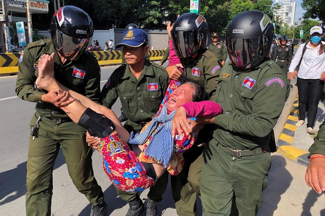 A woman is carried by police officers after security guards broke up a small protest near the Chinese embassy opposing alleged plans to boost Beijing's military presence in the country, in Phnom Penh, Cambodia on October 21, 2020. (Photo by Heng Mengheang/Reuters)