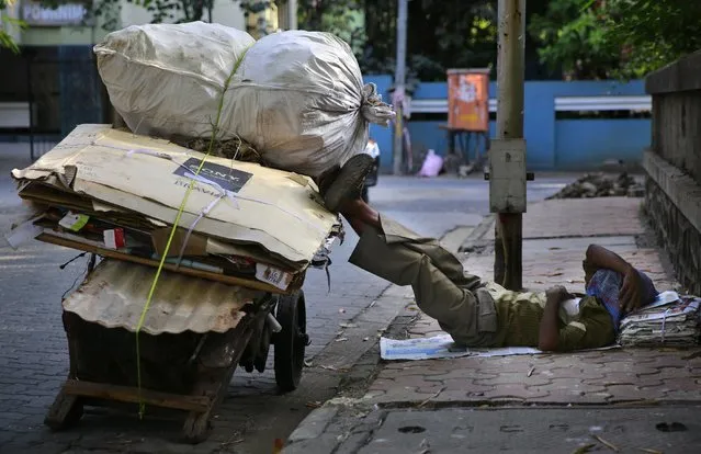 An Indian migrant laborer sleeps on a pavement next his handcart in Mumbai, India, Wednesday, January 21, 2015. Some 800 million people in the country live in poverty, many of them migrating to big cities in search of a livelihood and often ending up on the streets. (Photo by Rafiq Maqbool/AP Photo)