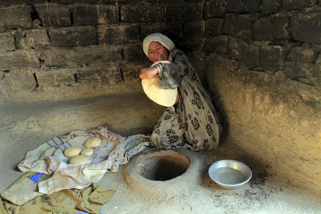 An Afghan woman bakes bread in her oven at their house outside Jalalabad, Afghanistan September 16, 2015. (Photo by Reuters/Parwiz)