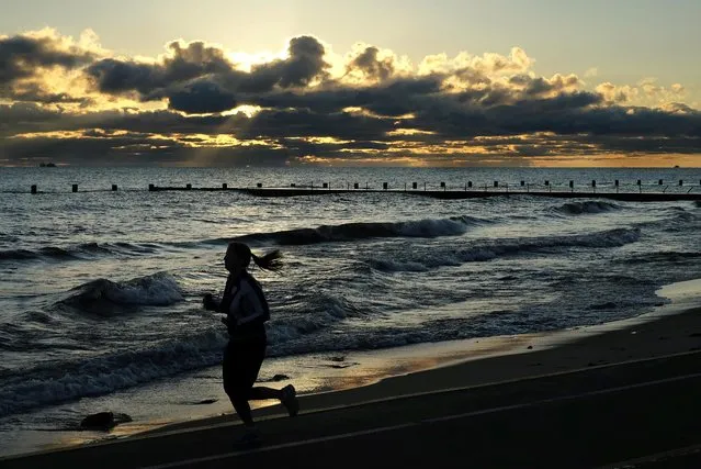 The sun rises over Lake Michigan as a runner jogs along the lakeshore, Monday, October 24, 2016, in Chicago. (Photo by Kiichiro Sato/AP Photo)