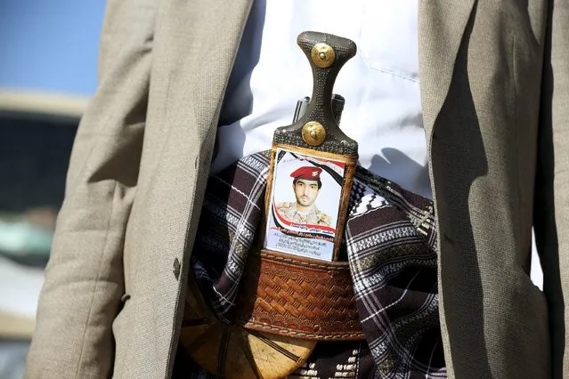 A tribal fighter loyal to Yemen's government carries a photo of a slain army officer loyal to Yemen's government in the country's northern city of Marib December 30, 2015. (Photo by Ali Owidha/Reuters)