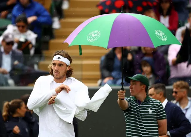 Greece’s Stefanos Tsitsipas stands by an umbrella as his first-round match against Austria’s Dominic Thiem is suspended due to rain at All England Lawn Tennis and Croquet Club in London, Britain on July 4, 2023. (Photo by Hannah Mckay/Reuters)