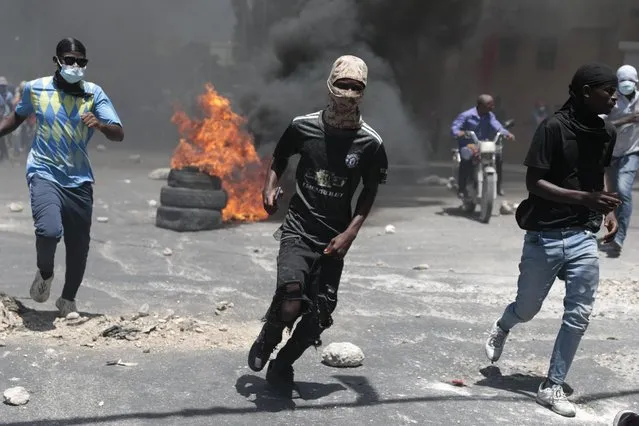 Protesters run for cover from tear gas fired by police during a protest against insecurity in Port-au-Prince, Haiti, Monday, August 7, 2023. (Photo by Joseph Odelyn/AP Photo)