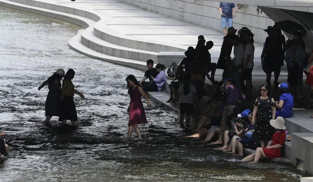 Visitors rest in the shade in the midday heat at Cheonggye stream in downtown Seoul, South Korea, Monday, July 23, 2018. The temperature in a city north of Tokyo reached 41.1 degrees Celsius (106 degrees Fahrenheit) on Monday, the highest ever recorded in Japan, as a deadly heat wave gripped a wide swath of the country and nearby South Korea. (Photo by Lee Jin-man/AP Photo)