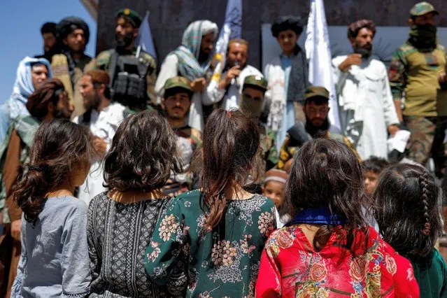 Afghan girls look at Taliban supporters on the second anniversary of the fall of Kabul on a street near the US embassy in Kabul, Afghanistan on August 15, 2023. (Photo by Ali Khara/Reuters)