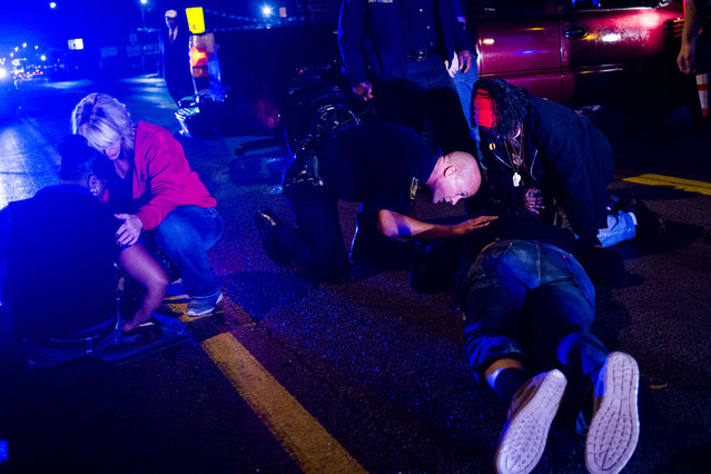 Flint Police Deputy Chief Devon Bernritter, center, checks on the status of a man lying in the street after a truck collided with into protesters calling for the right to form unions Tuesday, October 2, 2018, in Flint, Mich. (Photo by Jake May/The Flint Journal via AP Photo)