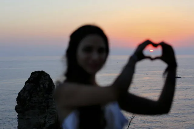 In this Friday, June 30, 2017 photo, a tourist makes the shape of a heart with her hands as she poses for a picture as the sun sets over the Mediterranean Sea in Beirut, Lebanon. The tourism industry in Lebanon is on the rebound, thanks in no small part to the misfortunes of its Middle East neighbors, engulfed by wars, chaos and political upheaval. (Photo by Hassan Ammar/AP Photo)