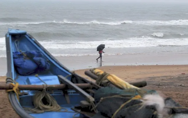 A man walks holding an umbrella during a drizzle at the Puri beach on the Bay of Bengalcoast in Odisha, India, Monday, May 24, 2021. Cyclone Yaas was forecast to hit the eastern states of West Bengal and Odisha on Wednesday. (Photo by AP Photo/Stringer)