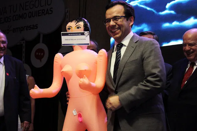 Chile's economy minister Luis Cespedes holds up an inflatable doll during an event of the exporters' association Asexma in Santiago, Chile, December 13, 2016. Picture taken December 13, 2016. The sign reads “To stimulate the economy”. (Photo by Jorge Cadenas Lorca/Reuters)