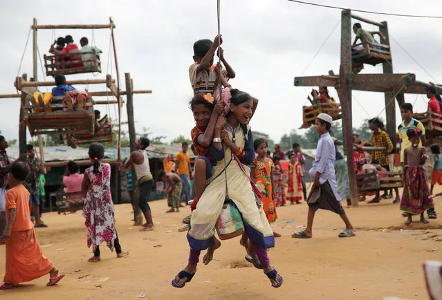 Rohingya refugee children ride on human-powered ferris wheels in the Kutupalong camp in Cox's Bazar, Bangladesh on August 24, 2018. (Photo by Mohammad Ponir Hossain/Reuters)