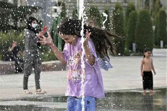 A girl enjoys a water fountain at the Ebrahim Park while temperature reaches 38 C (100.4 F) in Tehran, Iran, Tuesday, August 1, 2023. Iran announced a nationwide two-day, Wednesday and Thursday, holiday because of increasing temperatures. (Photo by Vahid Salemi/AP Photo)