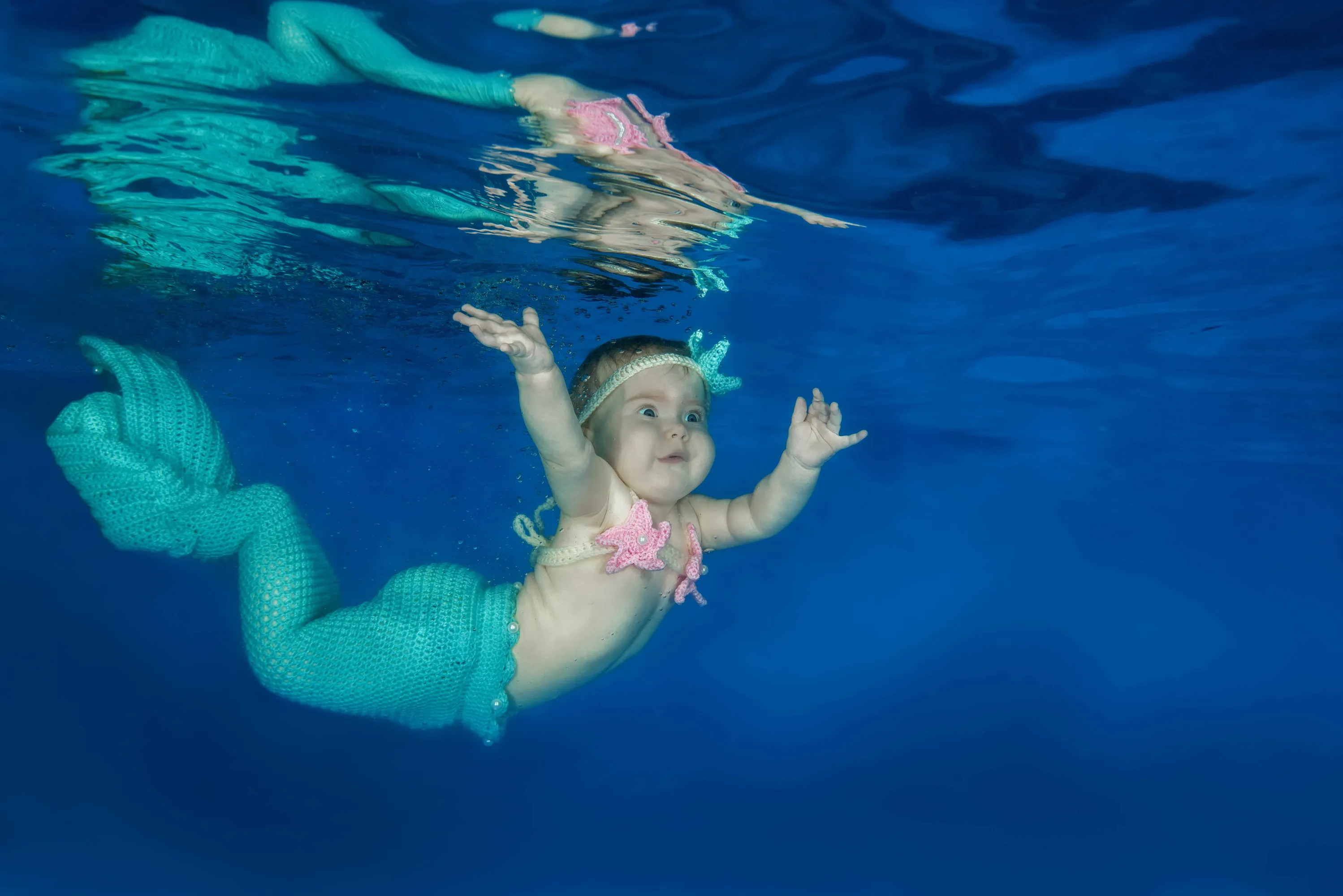 Next picture →. Infant in Christmas suit posing underwater in the pool on D...