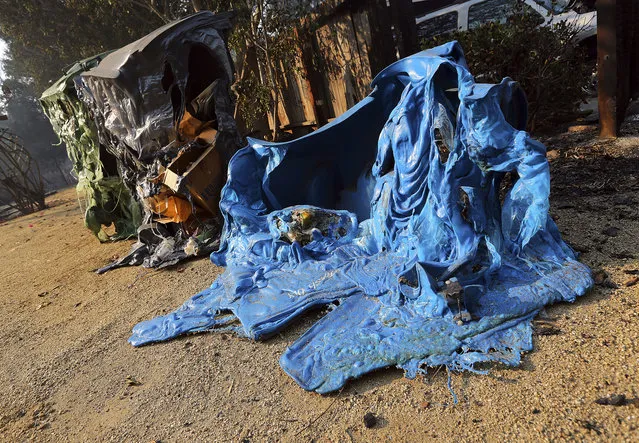 Melted recycling and trash containers stand next to one of at least 20 homes destroyed just on Windermere Drive in the Point Dume area of Malibu, Calif., Saturday, November 10, 2018. Known as the Woolsey Fire, it has consumed thousands of acres and destroyed dozens of homes. (Photo by Reed Saxon/AP Photo)