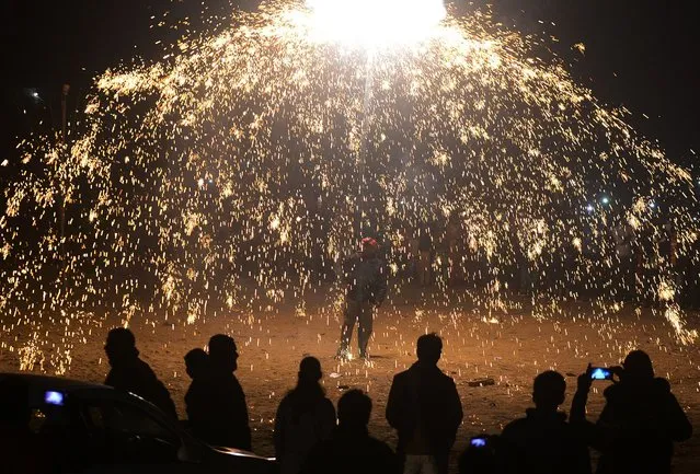 Indian Christian devotees watch a fireworks display marking Christmas Eve outside St. Peter's Church in Allahabad on December 24, 2016. (Photo by Sanjay Kanojia/AFP Photo)