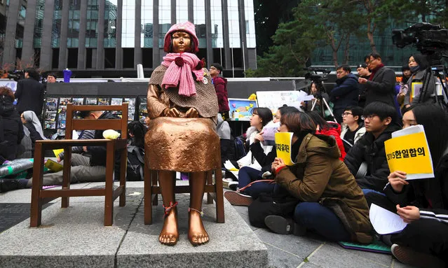 South Korean protesters sit near a statue of a teenage girl symbolizing former “comfort women”, who served as s*x slaves for Japanese soldiers during World War II, during a weekly anti- Japanese demonstration in front of the Japanese embassy in Seoul on November 21, 2018. South Korea on November 21 announced the formal shutdown of a controversial Japanese- funded foundation created to help former wartime s*x slaves – a move that will further sour ties between the neighbours. (Photo by Jung Yeon-je/AFP Photo)