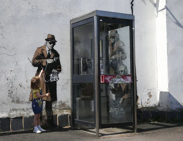 Polly Dreezer, age 3, points to graffiti art on a wall near the headquarters of Britain's eavesdropping agency, Government Communications Headquarters, known as GCHQ, in Cheltenham, western England April 16, 2014. British media have attributed the new work to acclaimed British street artist Banksy, as a spoof on recent government spying scandals exposed by former U.S. (Photo by Eddie Keogh/Reuters)