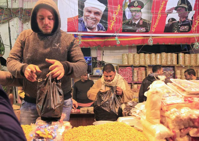 Street vendors sell nuts and traditional sweets as they celebrate Moulid Al-Hussein, the birthday of Prophet Mohammad's grandson Hussein in old Cairo, Egypt, February 10, 2016. Poster depicting Egypt's President Abdel Fattah al-Sisi is seen in the background. (Photo by Amr Abdallah Dalsh/Reuters)