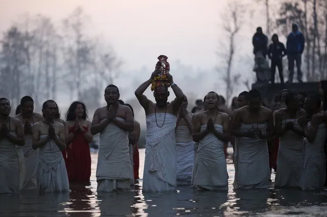 Devotees offer prayers before taking a holy bath in the Triveni River during the Swasthani Bratakatha festival in Panauti near Kathmandu, Nepal, February 12, 2016. (Photo by Navesh Chitrakar/Reuters)