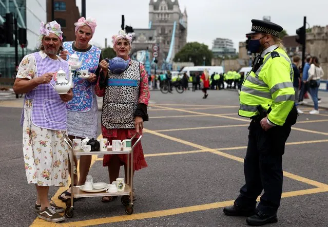 Police officer stands by Extinction Rebellion climate demonstrators attending a protest nearby the roadblock by Tower Bridge during a protest in London, Britain, August 30, 2021. (Photo by Tom Nicholson/Reuters)